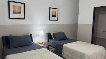 A hotel room with two beds, a bedside table with a lamp, and framed artwork on the wall.