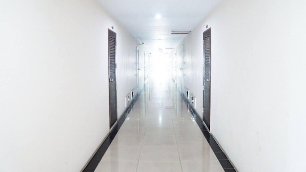 A long, narrow hallway with doors on both sides, a fire exit sign at the end, and a tiled floor. - Charoenkrung Place (Bangkok)