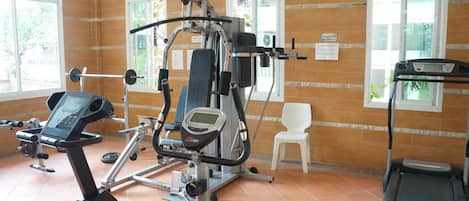 A gym with exercise equipment, a treadmill, and a white chair.