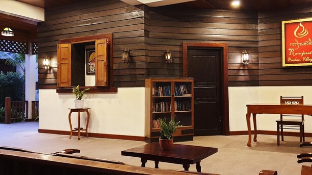 A wooden interior with a bookshelf, a table, and a chair. - Rainforest Huahin Hotel (Hua Hin)