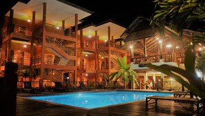 A multi-story hotel with a swimming pool, outdoor seating, and a covered area. - Rainforest Huahin Hotel (Hua Hin)