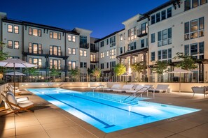 A swimming pool with lounge chairs and umbrellas, surrounded by multi-story buildings with balconies. - Locale Menlo Park (Menlo Park)