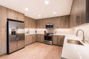 A modern kitchen with stainless steel appliances, wooden cabinets, and a white countertop. - Locale Menlo Park (Menlo Park)