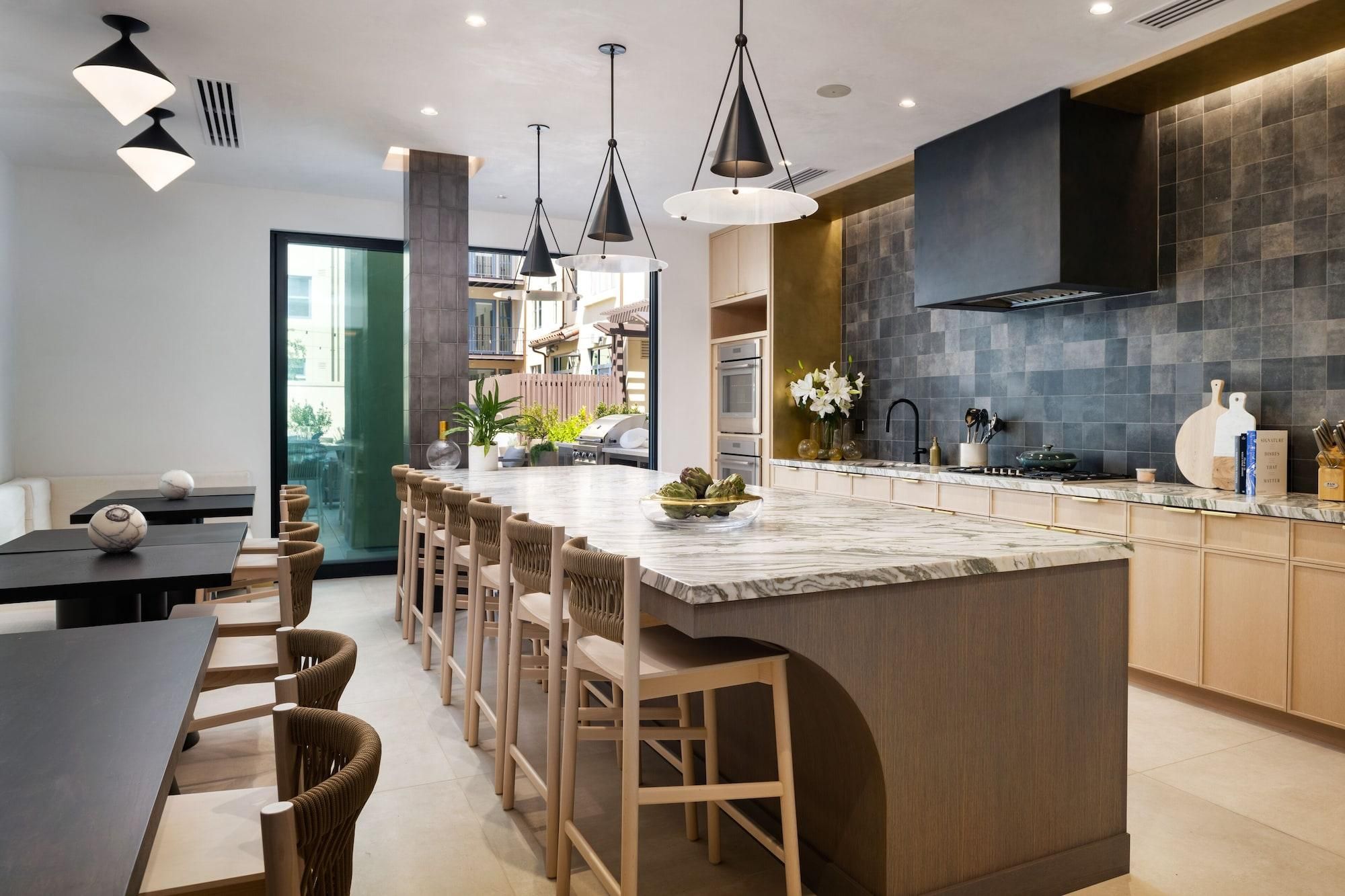 A modern kitchen with a central island, pendant lighting, and a view to an outdoor area.