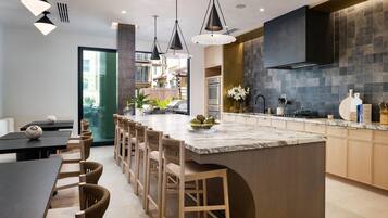 A modern kitchen with a central island, pendant lighting, and a view to an outdoor area.