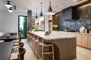 A modern kitchen with a central island, pendant lighting, and a view to an outdoor area.