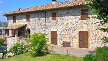 A stone building with a tiled roof, a bench, and a small garden area.