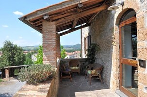 Un edificio de piedra con un patio cubierto, mesas al aire libre y vistas al campo.
