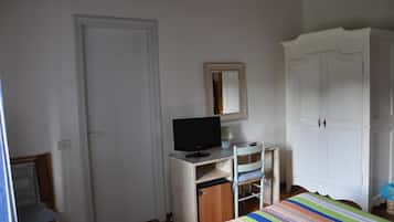 A bedroom with a bed, a desk with a computer, a wardrobe, and a mirror.