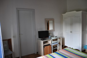 Un dormitorio con cama, un escritorio con computadora, un armario y un espejo.