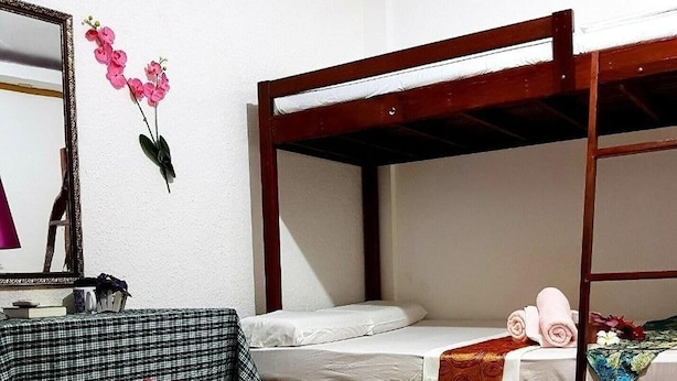 A hotel room with two bunk beds, a checkered headboard, a mirror, and a decorative pillow. - Hanbee S Resort (Puerto Princesa)