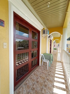 A covered corridor with a red door, white railings, and a tiled floor. - Hanbee S Resort (Puerto Princesa)