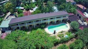 A large building with a swimming pool, surrounded by greenery. - Hanbee S Resort (Puerto Princesa)