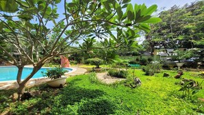 A lush garden with a swimming pool, various plants, and a well-maintained lawn. - Hanbee S Resort (Puerto Princesa)
