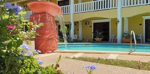 A pool with a water feature, a large planter, and a building with balconies. - Hanbee S Resort (Puerto Princesa)