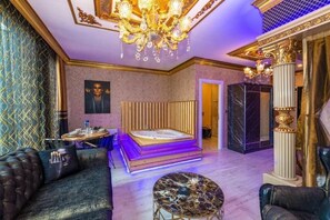 A luxurious bedroom with a large bed, a sitting area, a chandelier, and a marble coffee table. - By Mesut Resa Dence (Istanbul)