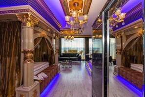 A luxurious room with a grand chandelier, ornate columns, and a plush sofa. - By Mesut Resa Dence (Istanbul)