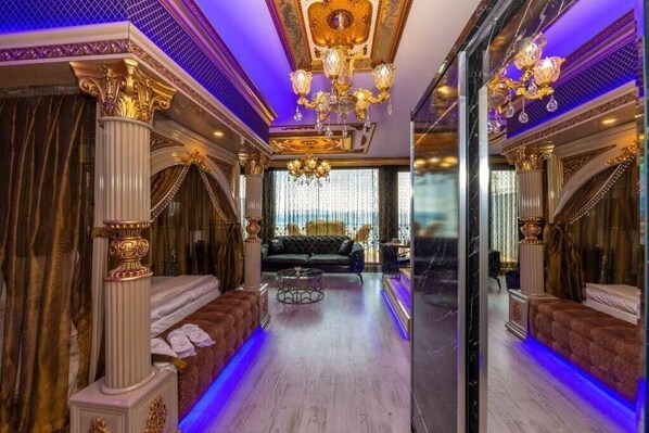 A luxurious room with a grand chandelier, ornate columns, and a plush sofa. - By Mesut Resa Dence (Istanbul)