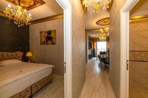 A bedroom with a large bed, a chandelier, and a painting on the wall. - By Mesut Resa Dence (Istanbul)