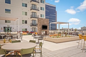An outdoor patio area with tables and chairs, a TV screen, and a barbecue grill. - Locale Midtown Phoenix (Phoenix)