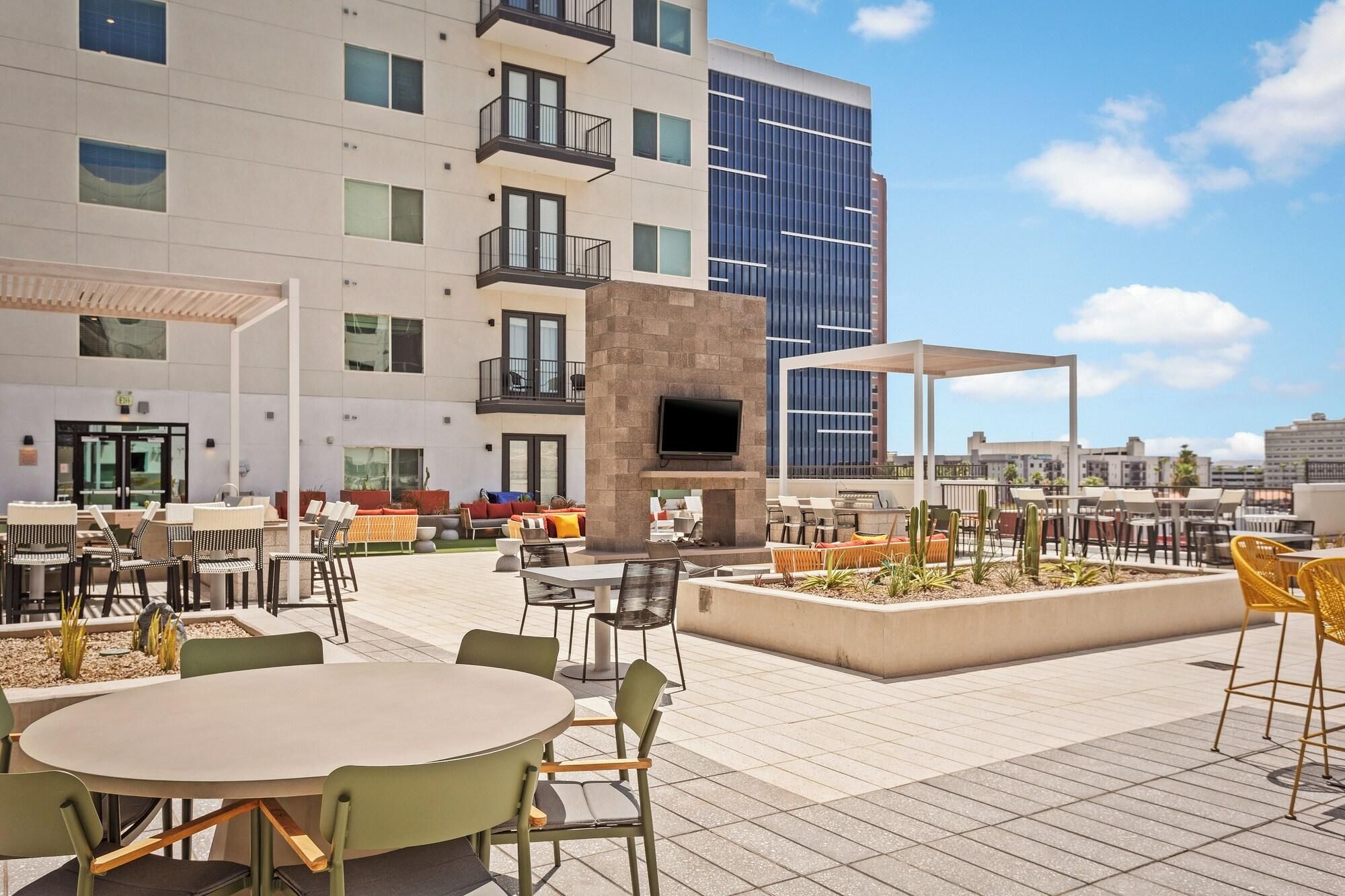 An outdoor patio area with tables and chairs, a TV screen, and a barbecue grill.