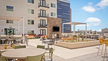 An outdoor patio area with tables and chairs, a TV screen, and a barbecue grill.