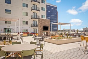 Un espace extérieur aménagé en terrasse, avec des tables et des chaises, un écran de télévision et un barbecue.