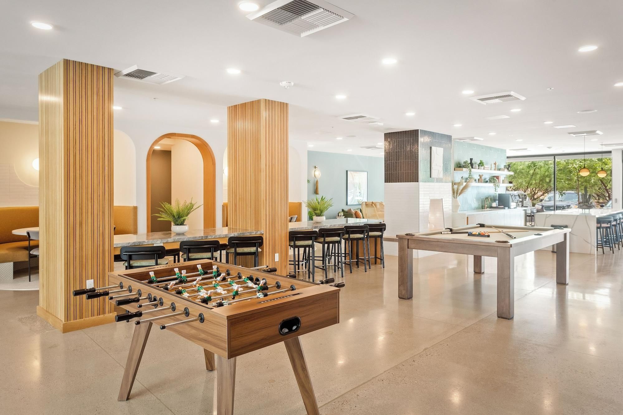A modern hotel lobby with a foosball table, seating area, and a pool table.