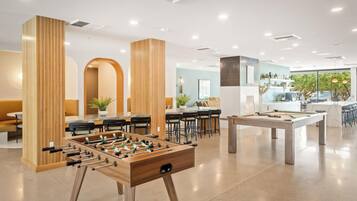 A modern hotel lobby with a foosball table, seating area, and a pool table.