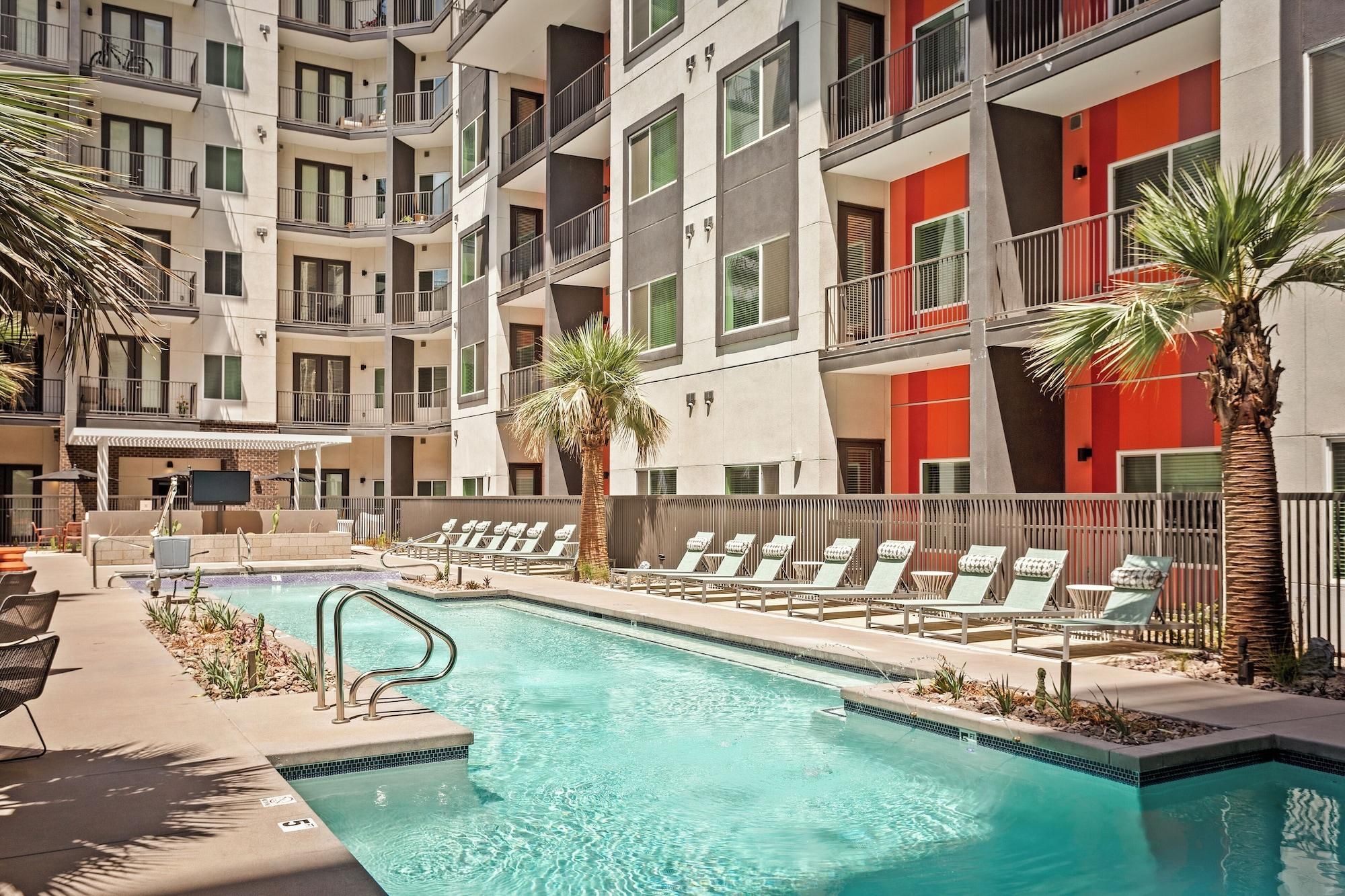 A multi-story hotel with a swimming pool, outdoor seating, and palm trees.