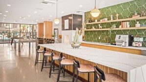 A modern bar area with a long counter, bar stools, and a green patterned wall. - Locale Midtown Phoenix (Phoenix)
