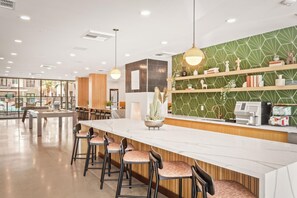 A modern bar area with a long counter, bar stools, and a green patterned wall. - Locale Midtown Phoenix (Phoenix)