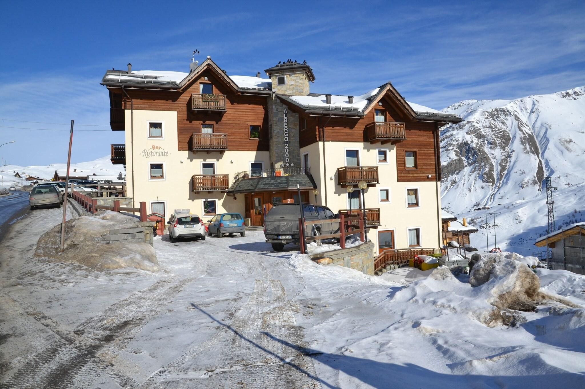 A two-story building with a bar and restaurant on the ground floor, surrounded by snow and parked cars.