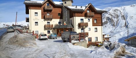 A two-story building with a bar and restaurant on the ground floor, surrounded by snow and parked cars.