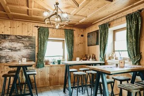 Un interior de madera con candelabro, cortinas verdes y una pizarra de menú.