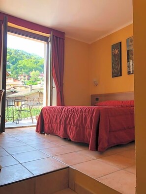Una habitación con cama, una mesa y vistas a un paisaje verde.