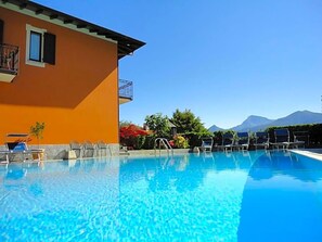 A clear swimming pool with lounge chairs and a building with a balcony. - Hotel Adler (Menaggio)