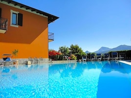 Piscina cristalina con sillas de descanso y un edificio con balcón.