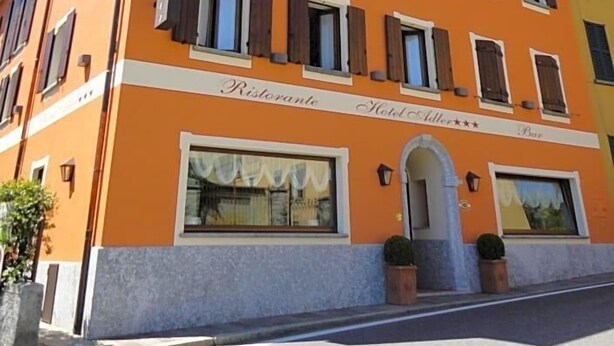 A multi-story building with a sign indicating it is a restaurant and hotel. - Hotel Adler (Menaggio)