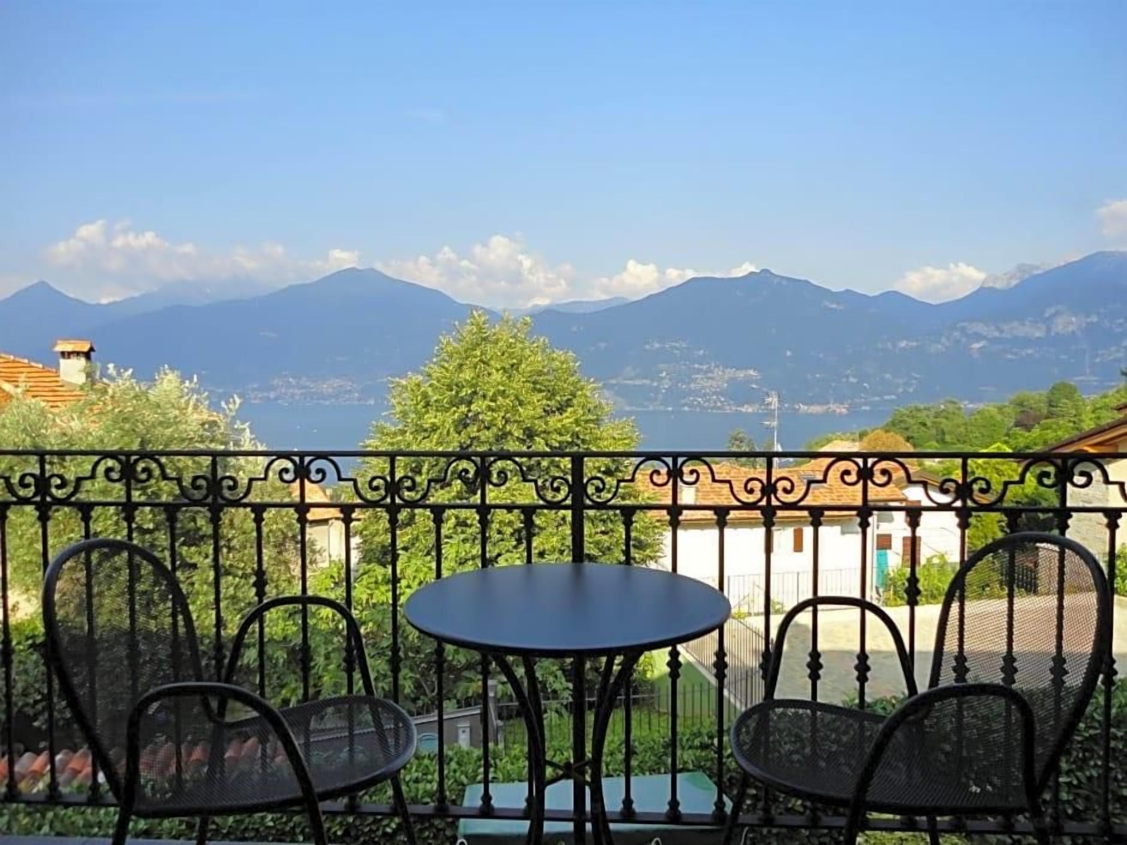 A balcony with a table and chairs, overlooking a mountainous landscape.