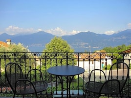 Un balcón con mesa y sillas, con vistas a un paisaje montañoso.