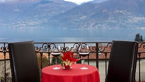 A table with two wine glasses and a red tablecloth, overlooking a mountainous landscape. - Hotel Adler (Menaggio)