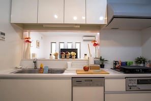 Una cocina moderna con lavavajillas integrado, ventana con vistas y encimera con tabla de cortar y fruta.