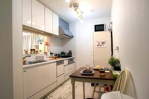 Une cuisine compacte avec des meubles blancs, un four à micro-ondes et un coin repas comprenant une table et des chaises.