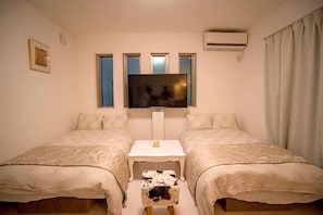 Una habitación con dos camas, televisión y aire acondicionado.