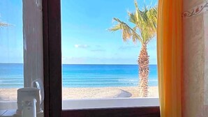 A bathroom with a view of a beach, a toilet, a towel rack, and a shower. - Hotel Egitarso Sul Mare (San Vito Lo Capo)