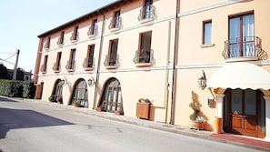 A multi-story building with balconies, arched windows, and a small entrance with a door. - Hotel Alla Nave (Masi)