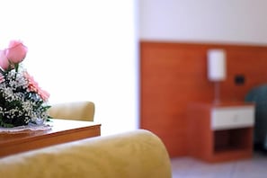 A hotel room with a wooden table, a floral arrangement, a bedside table, and a lamp. - Hotel Alla Nave (Masi)