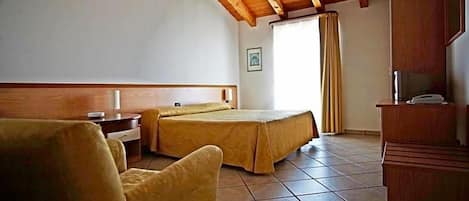 Habitación de hotel con dos camas, un escritorio, una silla, un televisor y una ventana con cortinas.