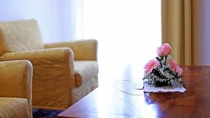 Una habitación con una mesa de madera, un sofá y un arreglo floral sobre la mesa.